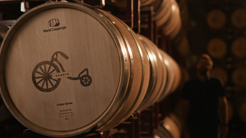Harken Wines Case Study Photo 9 Close-up of a wooden barrel with a logo of a penny-farthing bicycle etched onto its surface, labeled HARKEN.